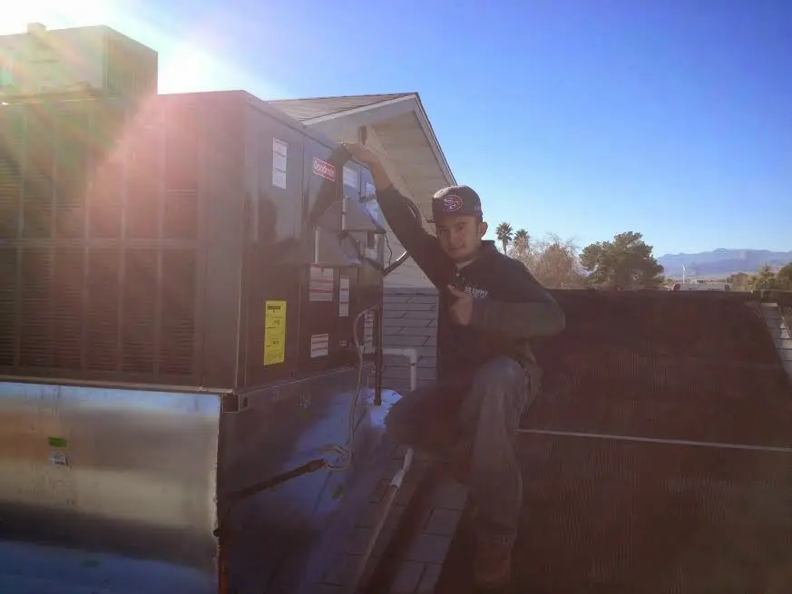HVAC technician performing AC Tune-Up on a rooftop unit in North Andover